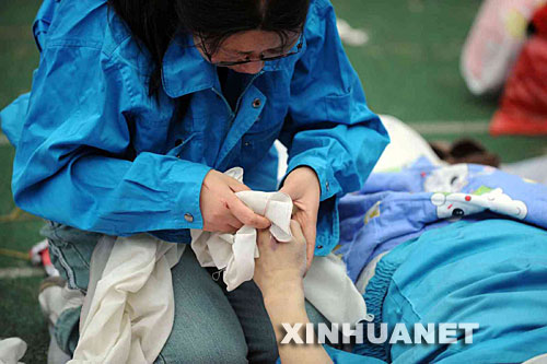5月14日，張關(guān)蓉在擦拭丈夫譚千秋的遺體。 受汶川地震影響，四川省德陽市東汽中學(xué)教學(xué)樓坍塌。在地震發(fā)生的一瞬間，該校教導(dǎo)主任譚千秋雙臂張開趴在課桌上，身下死死地護(hù)著4個(gè)學(xué)生，4個(gè)學(xué)生都獲救了，譚老師卻不幸遇難。 新華社記者王建華攝