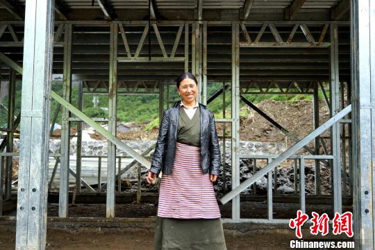 西藏隆子縣玉麥鄉(xiāng)位于中印邊境，是中國人口最少的行政鄉(xiāng)，全鄉(xiāng)56戶農(nóng)牧民將于今年搬遷至新房。圖為7月14日，玉麥鄉(xiāng)群宗站在框架已經(jīng)搭建好的新房門前，喜笑顏開?！〗w波 攝