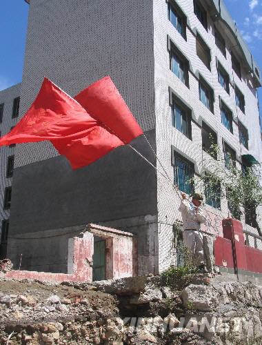  7月5日，一名防化兵高舉紅旗在北川縣城內(nèi)行走。當(dāng)日，記者經(jīng)特許進(jìn)入地震重災(zāi)區(qū)北川縣城采訪，用相機(jī)記錄下北川縣城的現(xiàn)狀。 